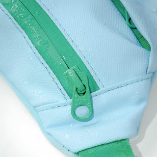 Close-up of light blue fanny pack showing water-resistant fabric and green zipper detail